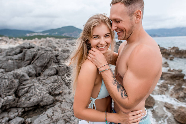 happy young couple in love spending time together on rocky beach in montenegro - Photo, Image