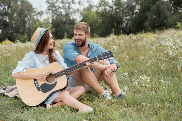 alegre mujer jugando la guitarra acústica a novio en verano archivado
 - Foto, imagen