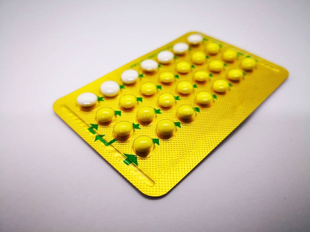 Oral contraceptive drug. 21 yellow pills consist of Ethinyl estradiol 0.035 mg. and Levonogestrel 0.15  mg. and 7 white pills placebo, for birth control. Abortion problem concept. Isolated on white background and selective focus. - Photo, Image