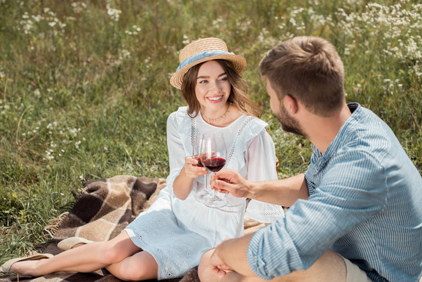 sonriente pareja tintineo vasos de vino tinto en verano campo
 - Foto, imagen