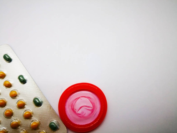 İlaç ve sağlık kavramı. Oral kontraseptif uyuşturucu gümüş blister ve Doğum kontrol kırmızı prezervatif. Kürtaj sorunu kavramı. Beyaz arka plan, seçici odak ve kopya alanı izole. - Fotoğraf, Görsel