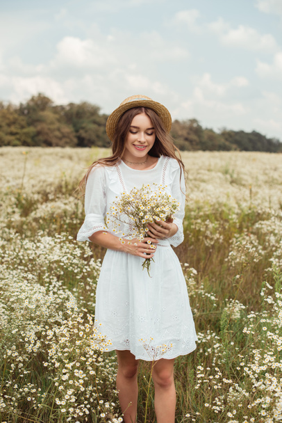 retrato de mujer bonita en vestido blanco con ramo de flores de manzanilla silvestre en el prado
 - Foto, imagen