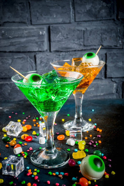 Karmivia herkkuja halloweenina, kirkkaan vihreä, appelsiinimartinin cocktail jääpaloilla ja vaahtokarkkisilmillä. Tummansinisellä pohjalla, tilaa tekstille
 - Valokuva, kuva