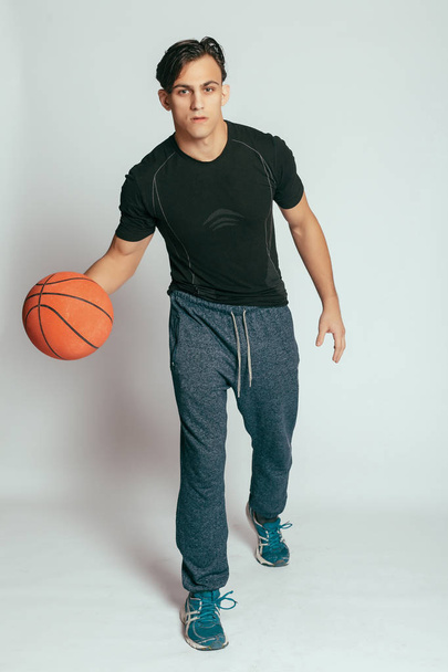 health, people, Sport and lifestyle concept - Real player. Handsome young smiling man carrying a basketball ball and looking at camera while standing against grey background - Фото, зображення