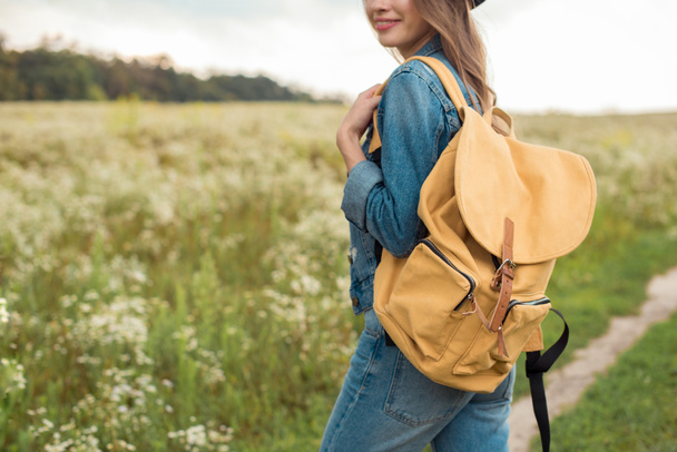 обрізаний знімок жінки з жовтим рюкзаком, що стоїть у полі
 - Фото, зображення