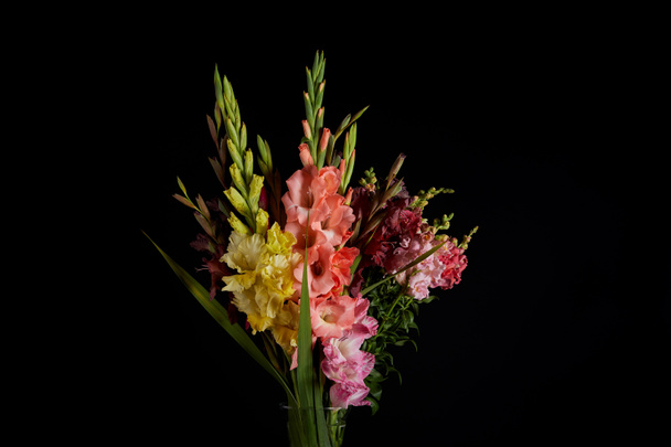 bouquet of beautiful pink, red, yellow and purple gladioli flowers isolated on black background - Photo, Image
