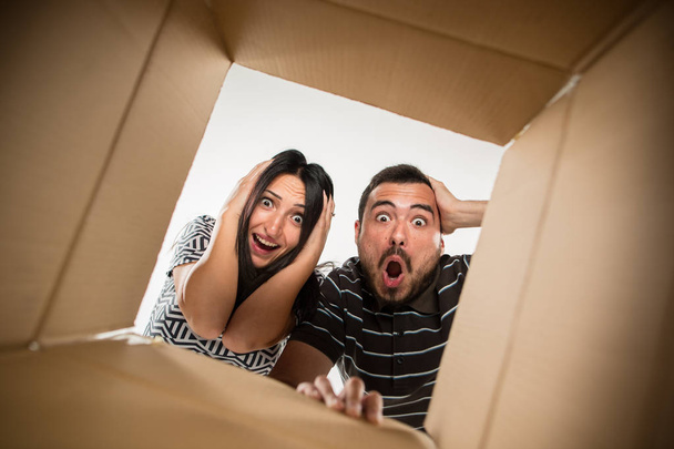 Пара розпаковує і відкриває картонну коробку і дивиться всередину
 - Фото, зображення