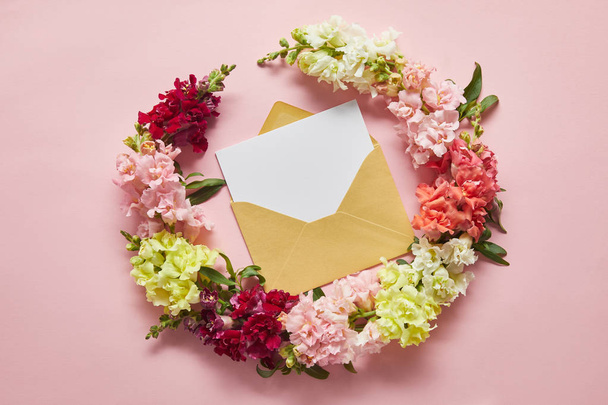 top view of beautiful tender flowers and blank card in envelope on pink - Foto, imagen