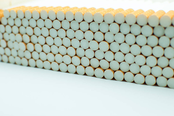 Multiple white cigarettes (tubes) with yellow filters in a row. Isolated - Fotó, kép