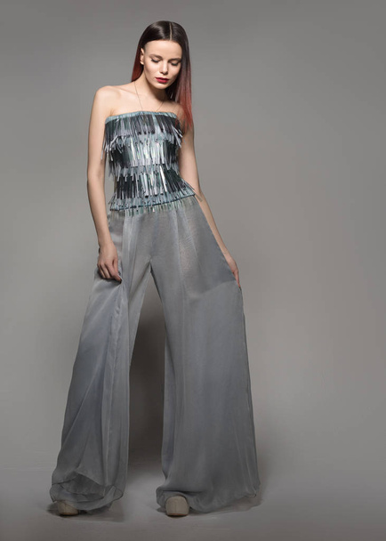 Fashion model in full length. Glamour Woman in wide-leg pants. A neutral grey background - Fotoğraf, Görsel