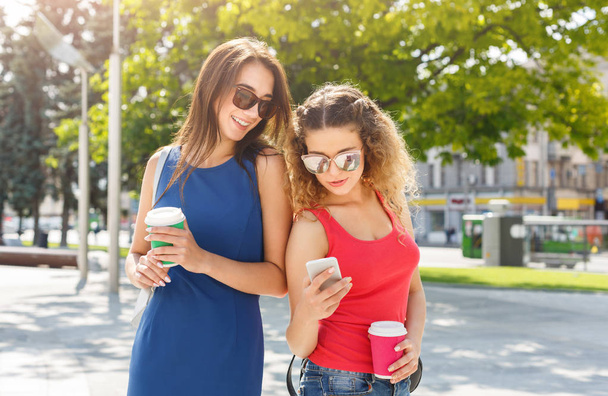Happy female friends with smartphone outdoors - Photo, Image
