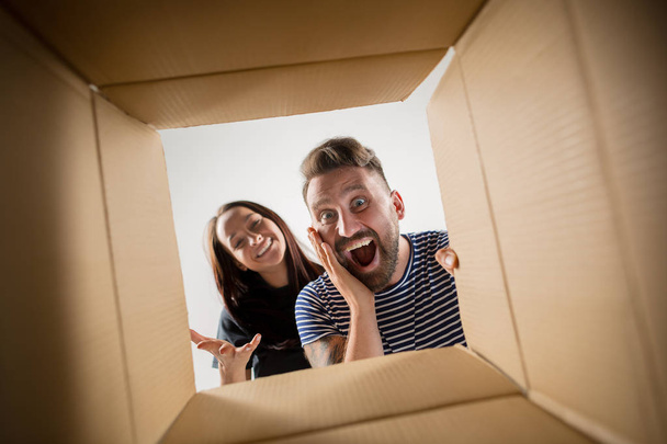 The couple unpacking and opening carton box and looking inside - Фото, зображення