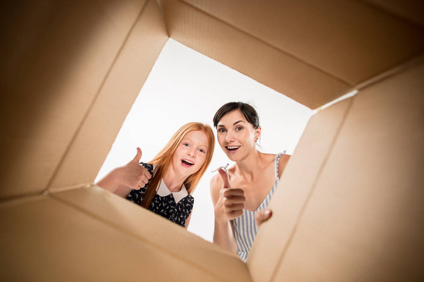 mom and daughter unpacking and opening carton box and looking inside - Фото, зображення