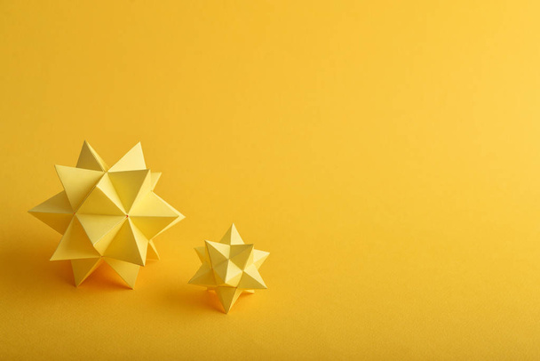 Two handmade yellow paper polyhedrons on a yellow background. - Φωτογραφία, εικόνα
