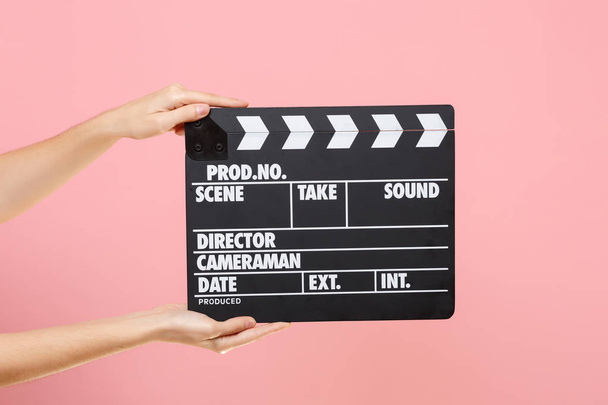 Close up female holding in hand classic director clear empty black film making clapperboard isolated on trending pastel pink background. Cinematography production concept. Copy space for advertising - Photo, Image