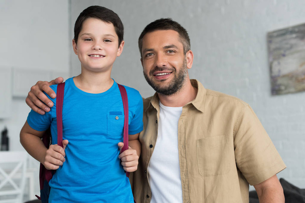 portrait of smiling father and son with backpack at home, back to school concept - Φωτογραφία, εικόνα
