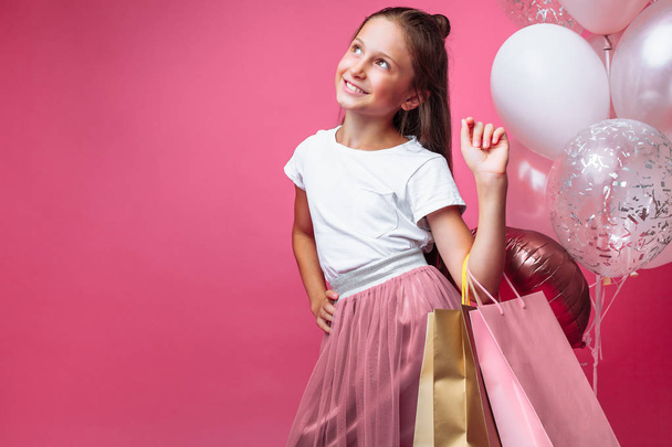 teen girl with shopping bags in hand, on pink background - Фото, изображение