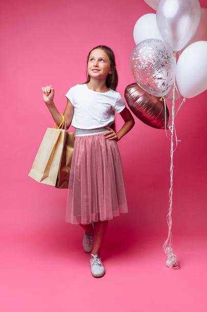 teen girl with shopping bags in hand, on pink background - Photo, Image