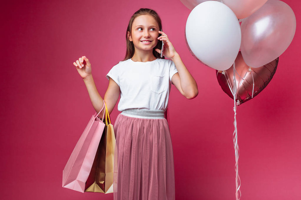 teen girl with shopping, talking on the phone, on a pink background - Fotografie, Obrázek