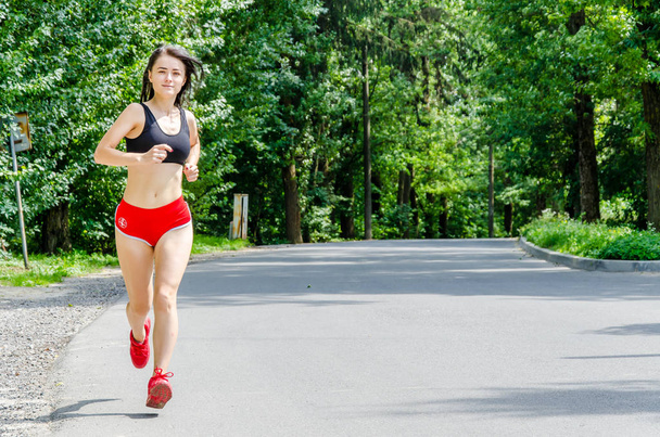 Mädchen in roten Shorts läuft im Park - Foto, Bild