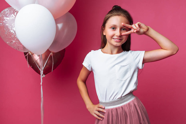 girl shows shows two fingers, portrait of teen girl on pink background - Photo, image