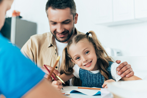 smiling father and kids doing homework together at home - Foto, Imagem