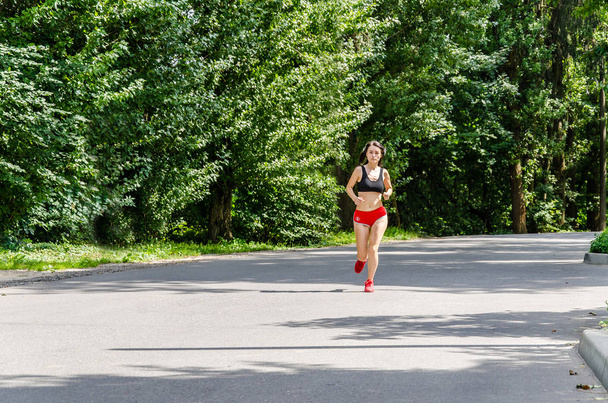 girl in red shorts is running in the park - Photo, Image