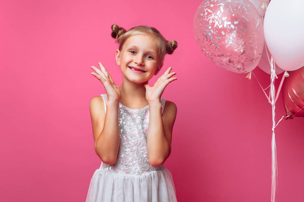 portrait of a little girl with balls, on a pink background in a photo Studio - 写真・画像