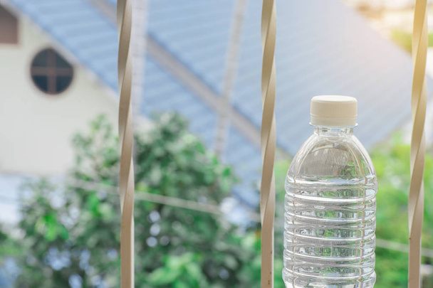 Pullo vettä tehty muovia taivaalla kotiin ja puu bokeh hämärtynyt
 - Valokuva, kuva