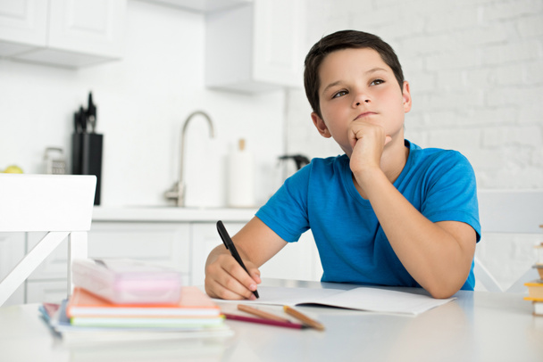 retrato del niño reflexivo haciendo la tarea solo en la mesa en casa
 - Foto, imagen