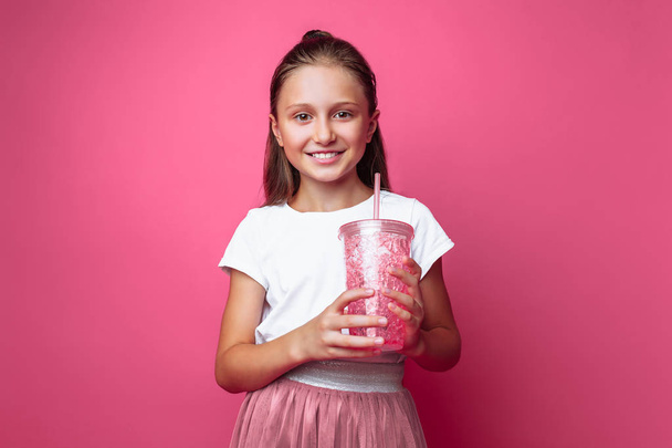 Beautiful girl with a drink or cocktail in her hands, on a pink background, in a photo Studio - Zdjęcie, obraz