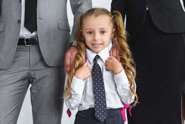 cropped shot of parents in suits and smiling kid in school uniform with backpack, back to school concept - Фото, изображение