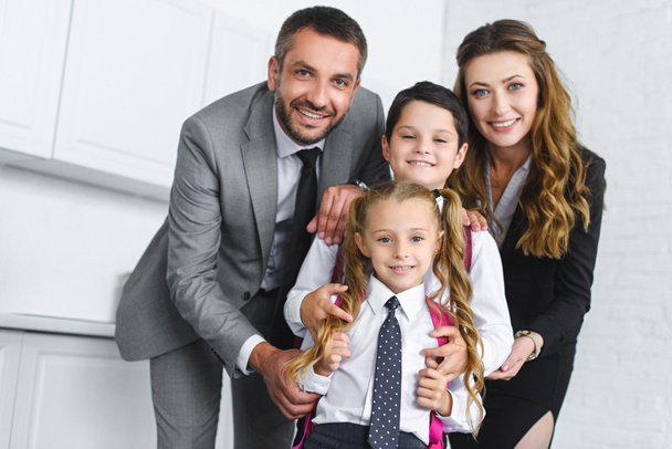 portrait of smiling kids in school uniform with backpacks and parents in suits at home - Valokuva, kuva