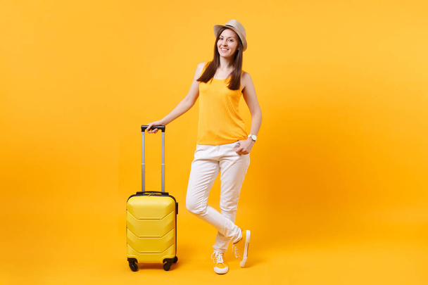 Мандрівник туристична жінка в літньому повсякденному одязі, капелюх з валізою ізольовано на жовтому помаранчевому тлі. Жінка-пасажир, що виїжджає за кордон для виїзду у відпустку у вихідні дні. Концепція авіаперельоту
 - Фото, зображення
