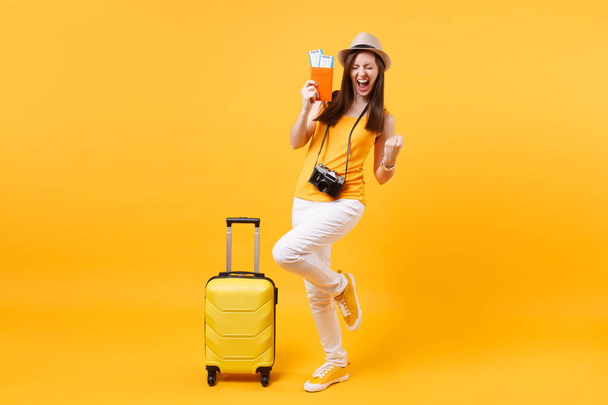 Emozionato donna turistica felice in cappello estivo con passaporto, biglietto, valigia, facendo gesto vincitore isolato su sfondo giallo. Femmina in viaggio all'estero per viaggiare week-end di vacanza. Concetto di volo aereo
 - Foto, immagini