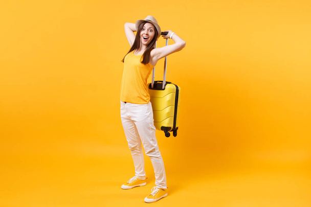Podróżny turystyczny Kobieta w letnie ubranie, kapelusz z walizką na białym tle na żółtym tle pomarańczowy. Kobiece pasażera podróżowania za granicą, podróż na weekendy wypad. Powietrze lot podróż koncepcja - Zdjęcie, obraz