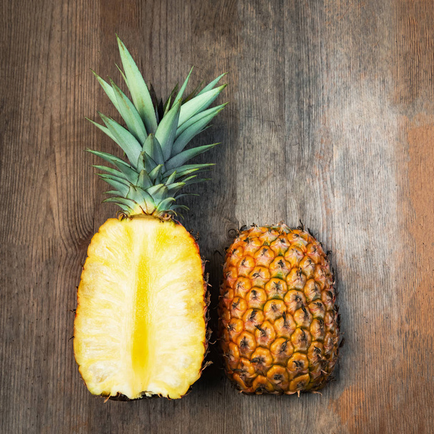 Ananas frutta tagliato due metà superiore spazio negativo sfondo in legno. Composizione quadrata. Succosa coltivata biologicamente matura e dolce
 - Foto, immagini