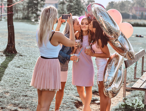 Радостные девушки фотографируются вместе на пикнике под открытым небом. Сцена празднования дня рождения в открытом парке
. - Фото, изображение