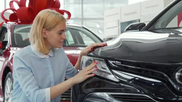 Beautiful woman smiling to the camera while exaining a new automobile - Footage, Video