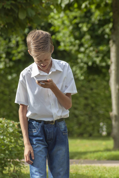 the boy emotionally speaks in the park by phone in summer day - Fotó, kép
