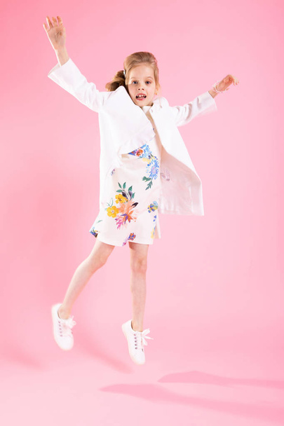 A teenage girl in light clothes jumped on a pink background. - Photo, Image