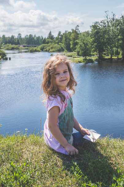 girl, a child sitting on a rock near the water - Фото, зображення