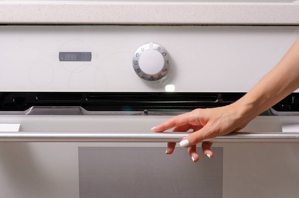 In the kitchen, the oven hob female hand - Zdjęcie, obraz