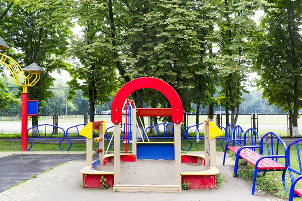 Parco giochi multicolore con una sabbiera su uno sfondo di alberi verdi
, - Foto, immagini