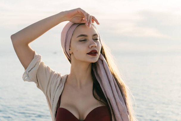 beautiful luxurious young woman with a headscarf on her head enjoys a holiday on a yacht, summer weather - Foto, afbeelding