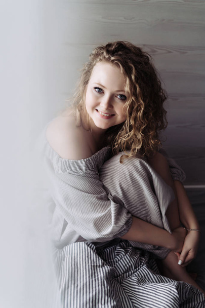 charming curly-haired woman in beautiful dress resting, looking at camera and smiling - Foto, Imagen