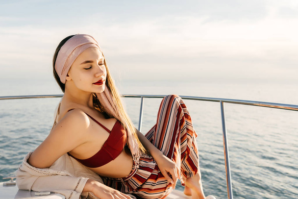 a tranquil, stylish girl in fashionable pants rests on a yacht in the sun, a long-awaited vacation - Foto, immagini
