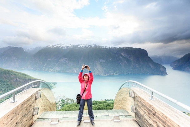 Tourism and travel. Woman tourist nature photographer taking photo with camera, enjoying Aurland fjord landscape from Stegastein lookout, Norway Scandinavia. - Foto, afbeelding