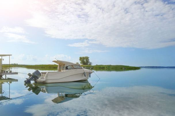 Ylellinen kalastus moottori vene ankkuroitu rannikolla lahdella joella tai järvellä. Scenic sininen taivas pörröinen valkoinen pilvet taustalla. Matkailu, seikkailu ja virkistys matka käsite
 - Valokuva, kuva