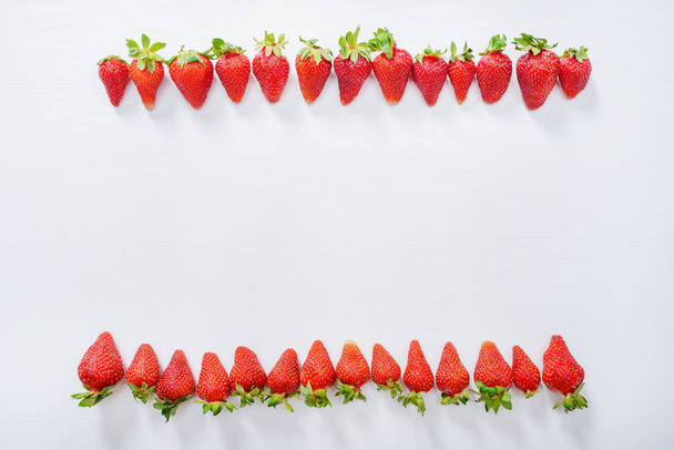 strawberry fruits in a row on white wood table background. - Фото, зображення